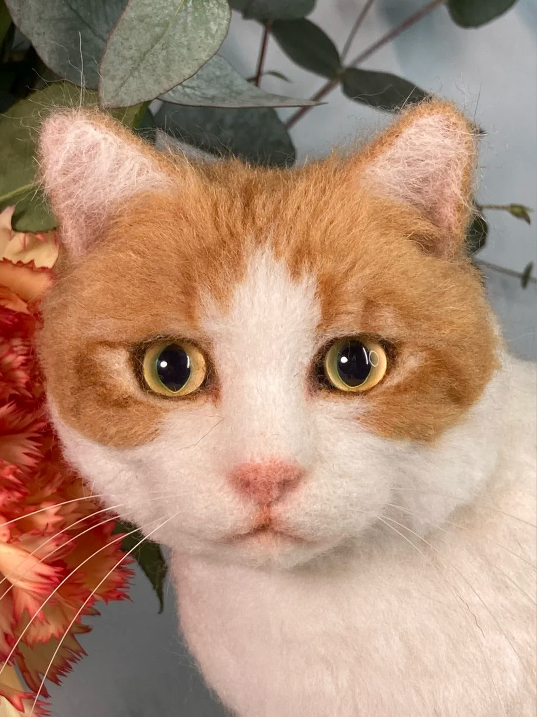 Cat with green eyes and white fur surrounded by flowers and leaves