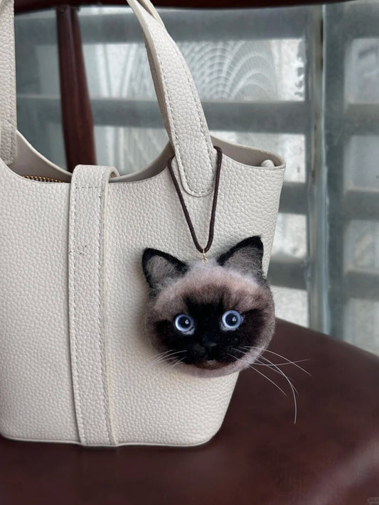White handbag with a cat-shaped patch on a wooden surface