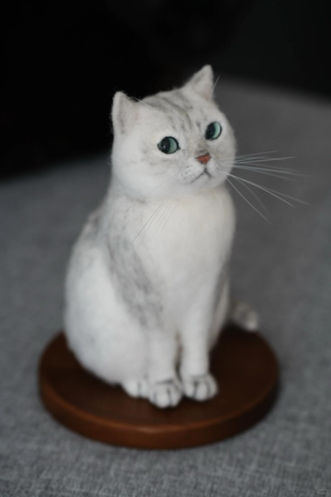 Cat figurine on a brown base with a dark background