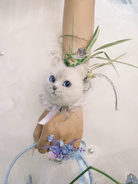 Decorative wrist corsage with a small white cat figurine on a plain background