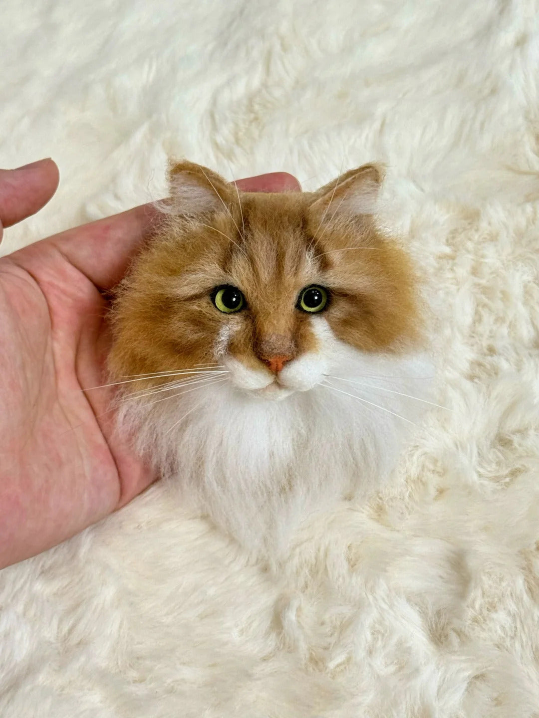 Small orange and white cat being held on a fluffy white surface