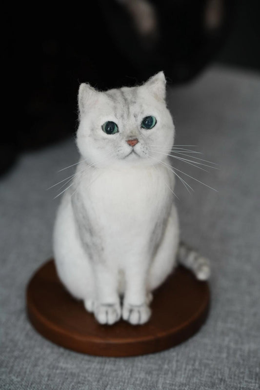 White cat figurine on a brown round base against a gray background