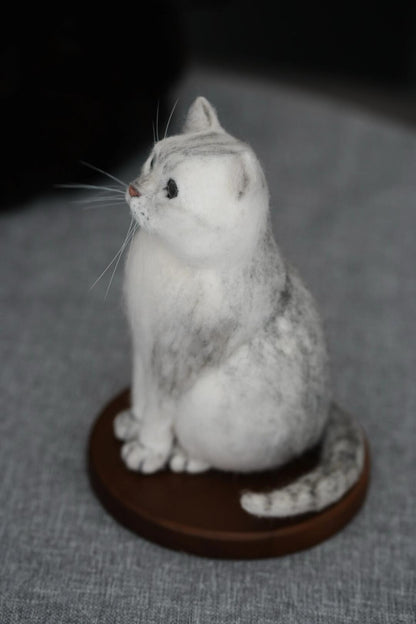 Felted sculpture of a gray cat on a dark brown stand against a gray background