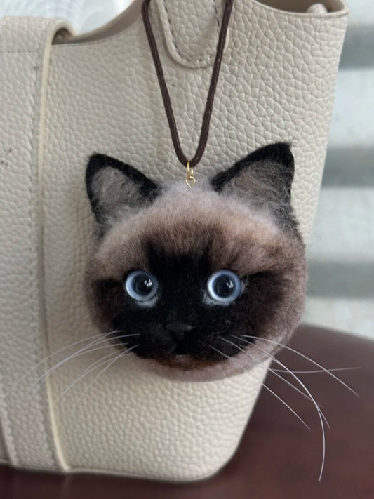 Cat-shaped keychain attached to a beige textured bag