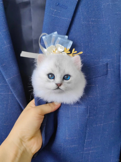 White cat-shaped brooch with blue eyes held against a blue suit background