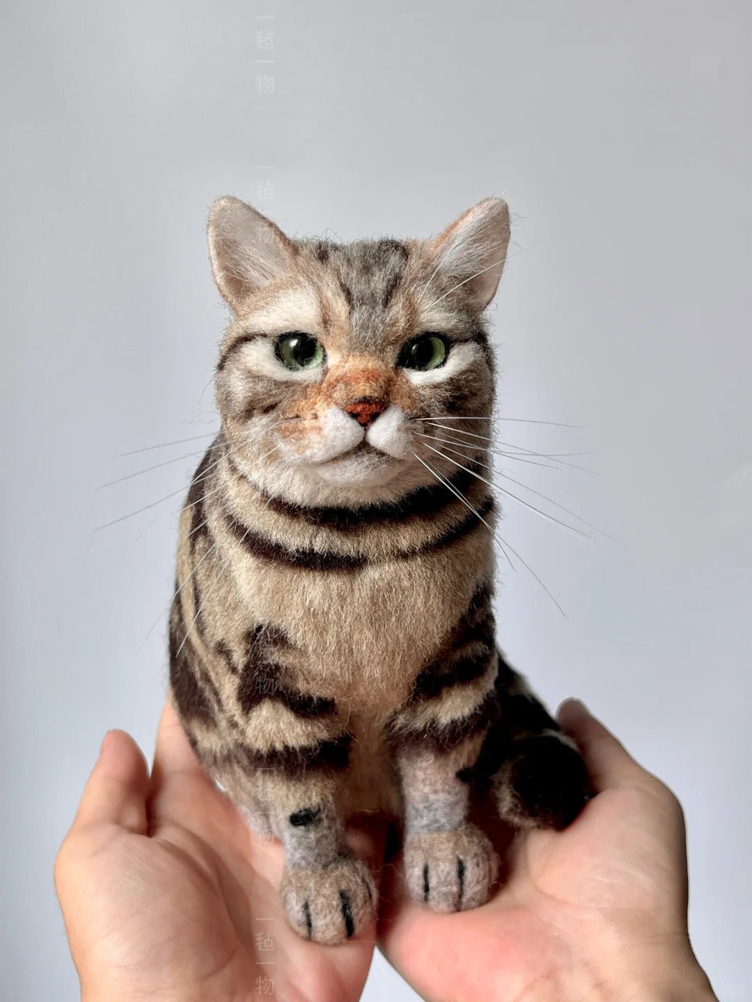 Textured cat sculpture held in hands against a plain background
