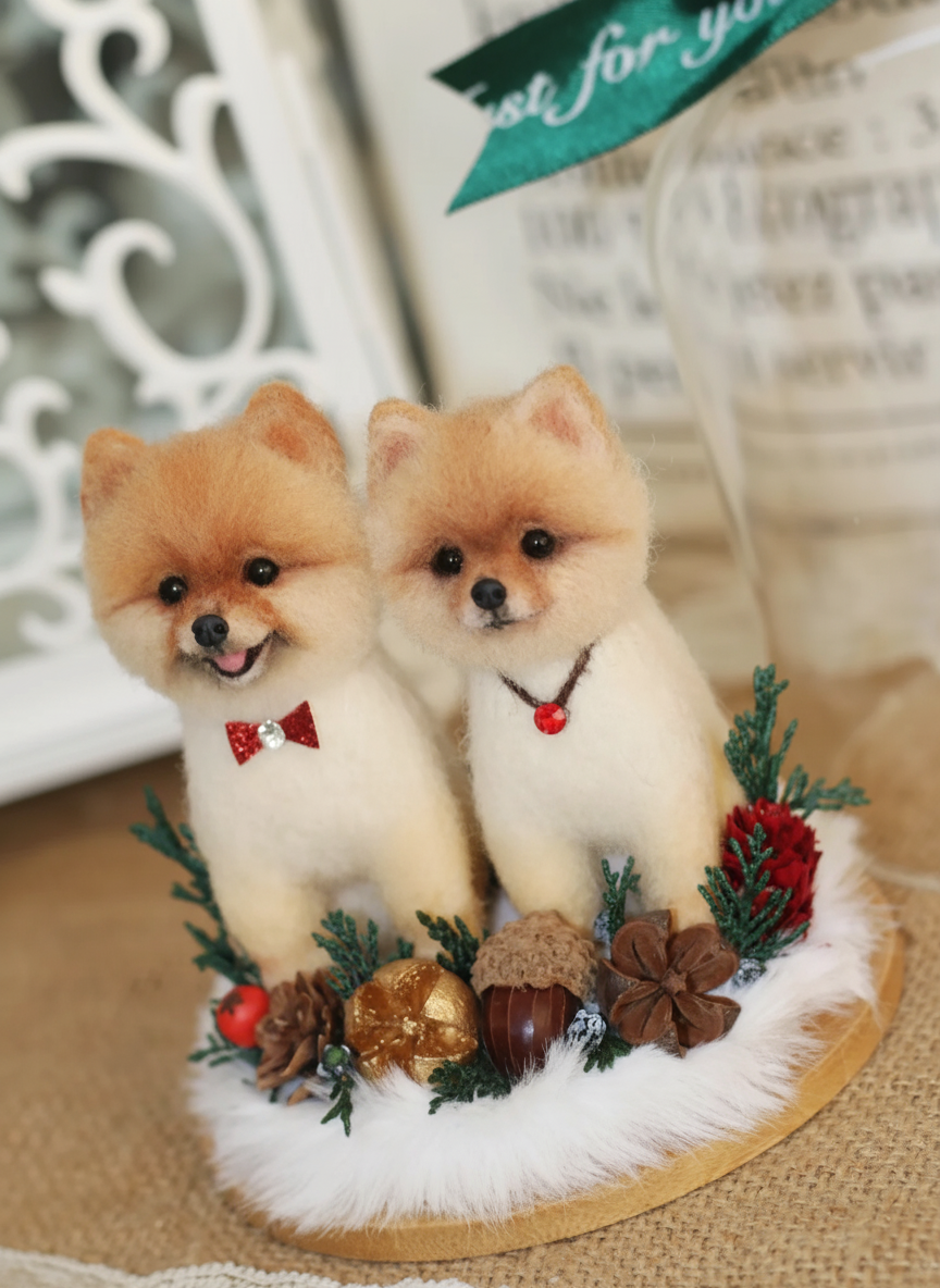 Two small dog figurines with festive decorations on a decorative stand.