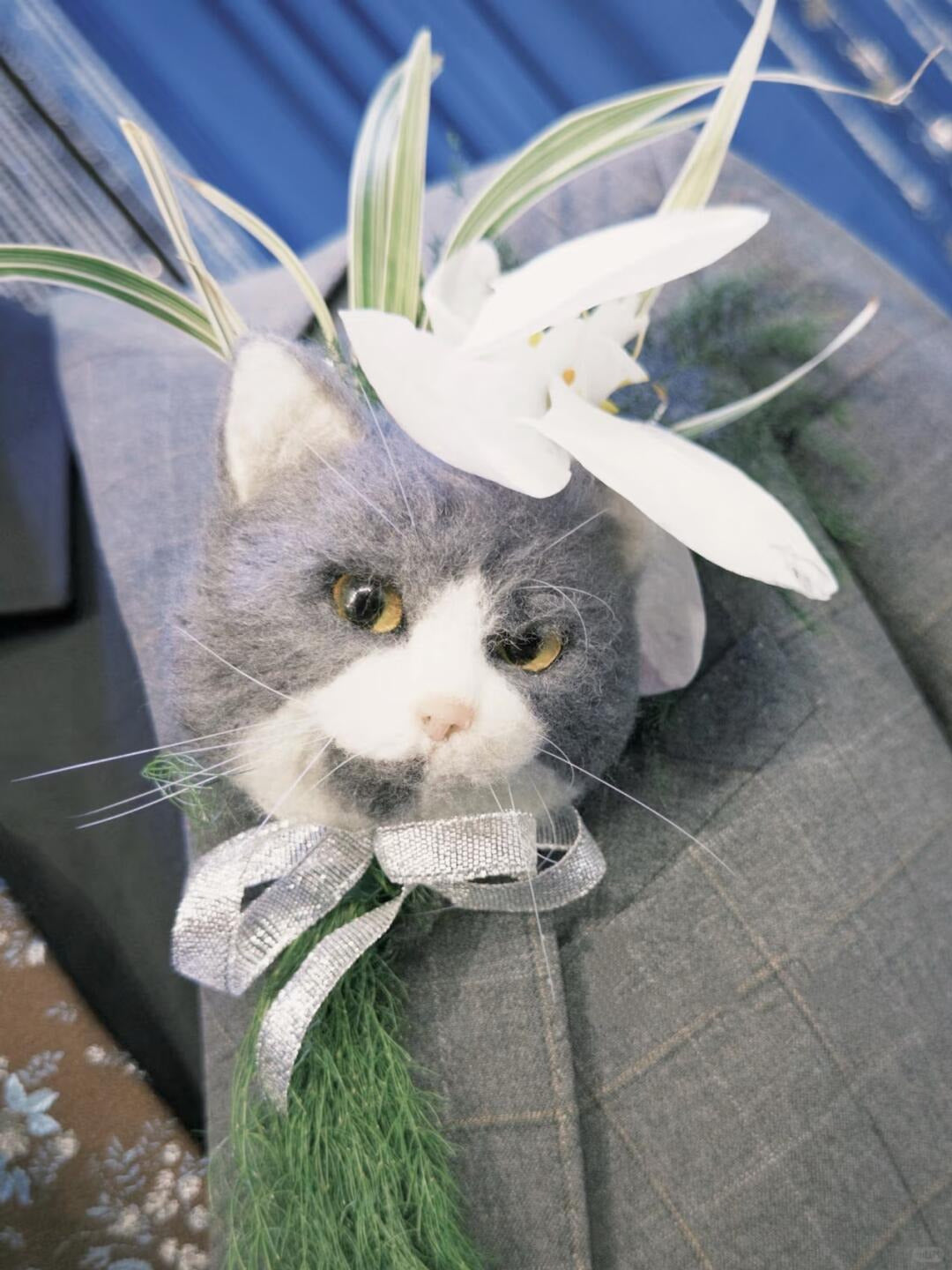 Cat wearing a decorative headband with flowers and ribbons on a blue background