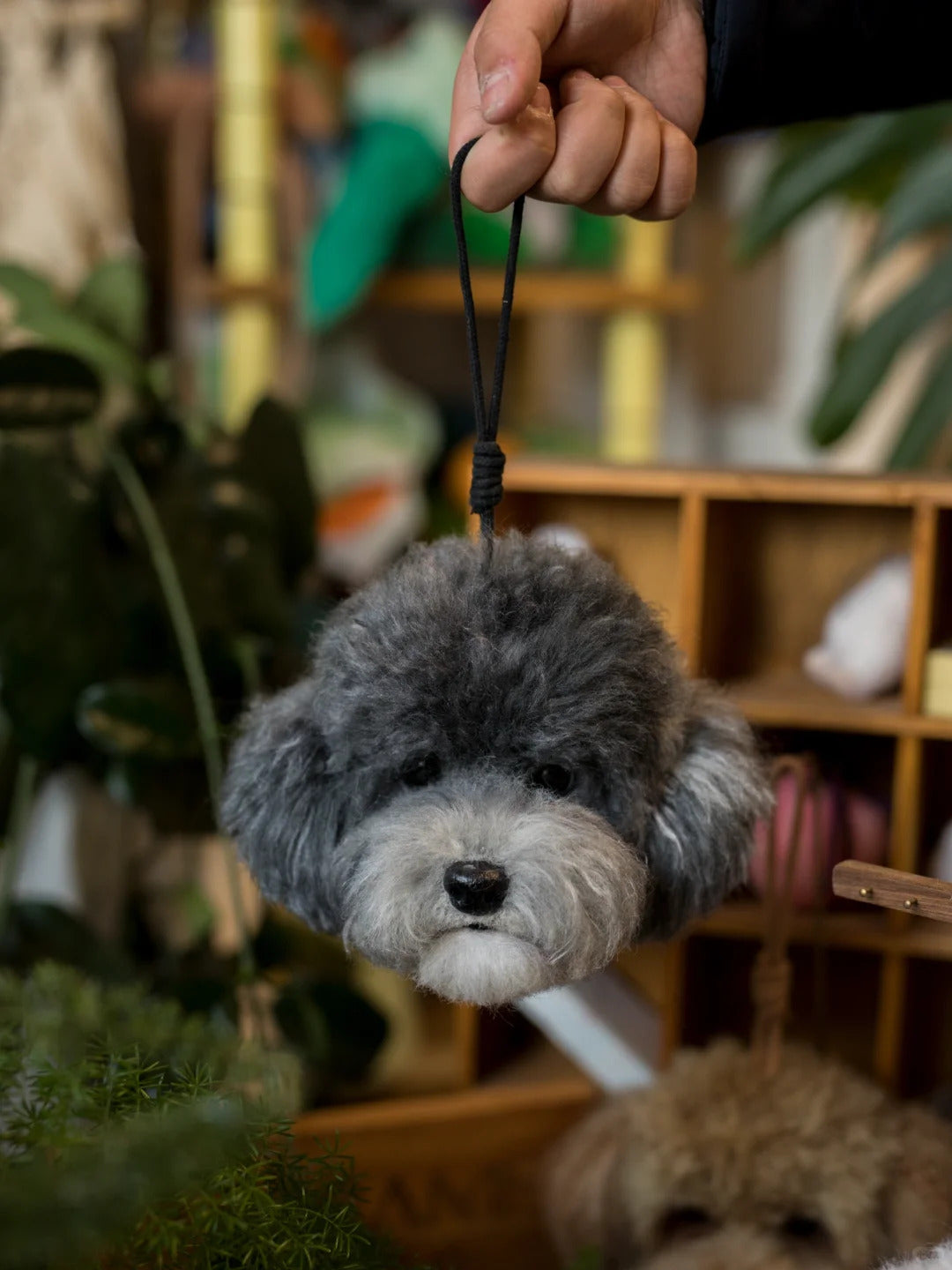 Keychain shaped like a dog's head held by a hand with a blurred indoor background