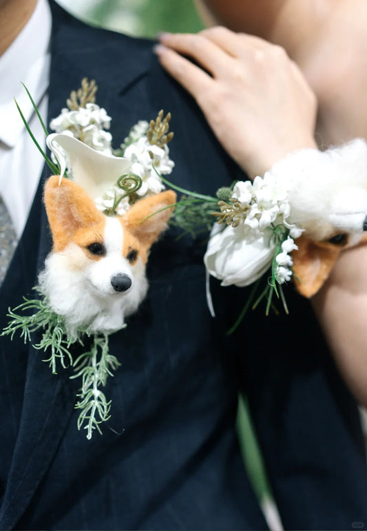 Dog wearing a boutonniere with white flowers and greenery on a dark suit.
