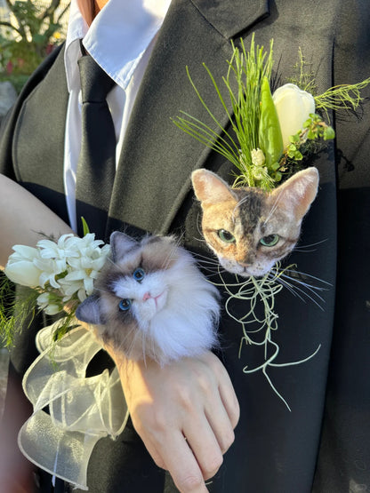 Two cats with floral decorations on a person's lapel and hand.